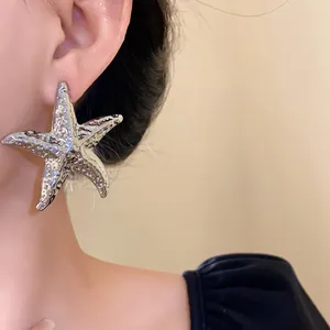 Detailed macro view of a large textured metallic silver starfish earring worn by a model