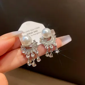 Primo piano di eleganti orecchini in argento con perle bianche e cristalli