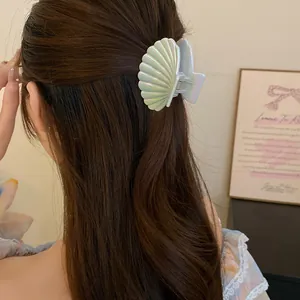 Elegant close-up of a pearlescent shell pleated hair claw clip styled in wavy hair