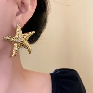 High-quality close-up of a textured gold metal starfish stud earring worn on an ear