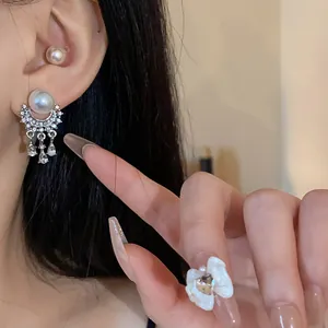 Primo piano di eleganti orecchini a nappa con perle e strass indossati sull'orecchio