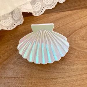 Close-up of iridescent shell hair claw clip with pearlescent finish on wooden background