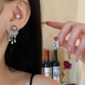 Primo piano di eleganti orecchini a nappa con perle e ago in argento e diamanti di lusso