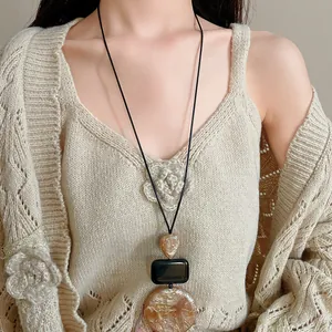 Close-up view of vintage resin sweater necklace with amber-toned geometric pendant details