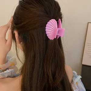 Detailed view of a sweet pink shell-shaped hair claw clip styled on long brown hair