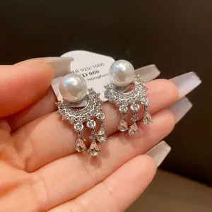 Primo piano di eleganti orecchini a nappa in argento con perle bianche e cristalli lucenti