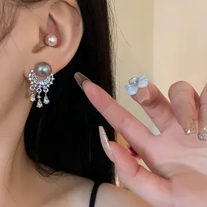 Eleganti orecchini a nappa in argento con perle e cristalli indossati su un orecchio