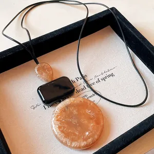 Detailed view of the resin necklace with amber-colored geometric pendants on tray.