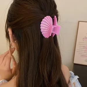 Close-up detail of a decorative pink shell hair claw clip styled in long brown hair for a sweet look