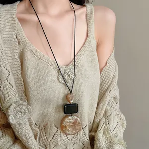 Detail shot of a vintage resin necklace featuring geometric pendants on a beige sweater
