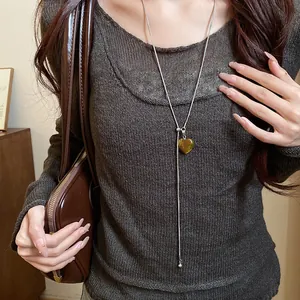 Elegant detail of a heart-shaped tiger eye stone pendant necklace on a long silver chain