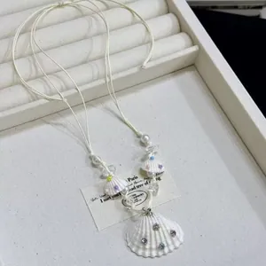 Close-up detail of shell pendant necklace with colorful rhinestones on white wax cord