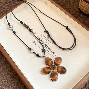 Macro detail of a vintage flower pendant necklace featuring amber cat's eye stones.