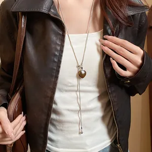 Close-up of vintage tiger eye heart pendant necklace on model wearing a leather jacket
