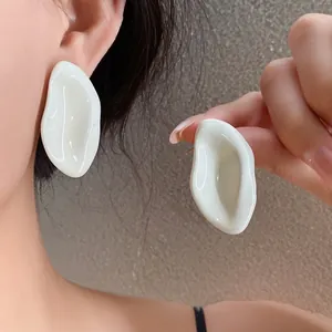Elegantes pendientes minimalistas de aceite de gota ovalados irregulares crema en modelo