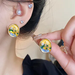 Detail of enamel flower pearl earrings with elegant yellow and green drip oil design.