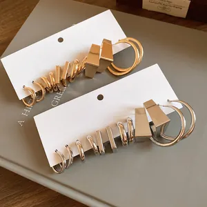 Minimalist geometric earring set in gold and silver finish featuring hoops and studs.