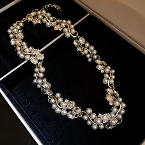 Close-up detail of a vintage style pearl and rhinestone necklace on black velvet
