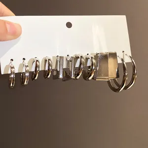 Close-up of a silver geometric earring set with hoops and wide rectangular studs