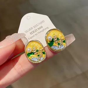 Detailed macro view of elegant enamel flower pearl earrings displayed on a silver card