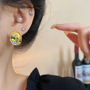 Close-up of elegant silver needle yellow enamel floral earrings with a pearl detail.