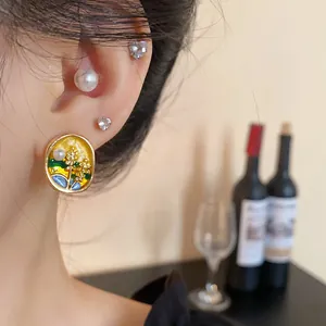 Detailed close-up of elegant floral enamel earrings with pearl accents worn on ear