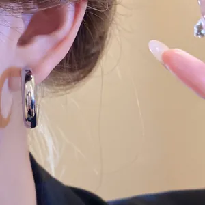Macro detail of a high-polish silver hoop earring worn on a model's ear