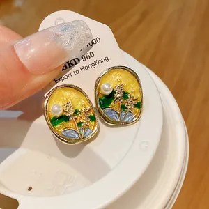Detail view of enamel floral earrings with pearl on a silver needle for women