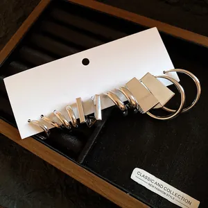 Close-up of polished silver geometric earrings on a white card within a jewelry tray
