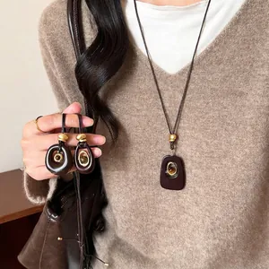 Dettaglio di un'elegante collana con pendente in resina occhio di tigre su maglione