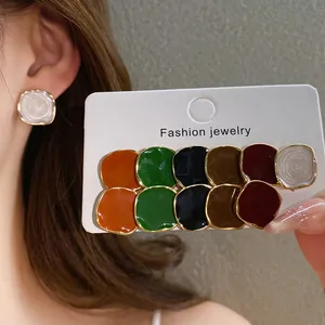 Close-up view of a 12-piece colorful enamel round stud earrings set on a white display card
