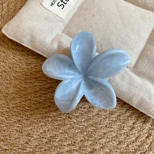 Dettaglio di un fermaglio per capelli in acrilico azzurro con design a fiore marmorizzato