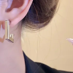 Detailed close-up showing a minimalist silver geometric earring with a high-polished finish