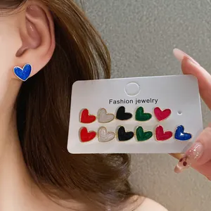 Close-up of colorful heart-shaped enamel stud earrings set with gold borders