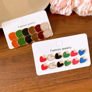 Close-up view of colorful heart and round drip oil stud earring set displayed on white cards