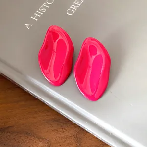 Primer plano de pendientes de esmalte rosa ovalados irregulares sobre gris