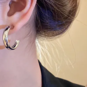 Detailed macro view of a minimalist silver-tone chunky hoop earring worn on the ear