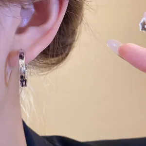 Detailed close-up showing minimalist polished silver hoop earrings worn on a female ear