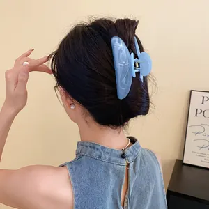 Dettaglio di un'elegante pinza per capelli in acrilico marmorizzato blu su uno chignon