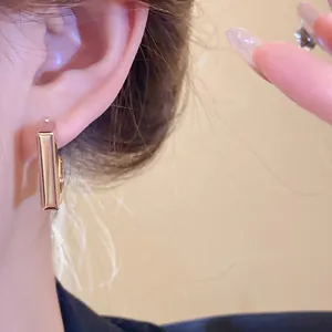 Detailed close-up shot of a minimalist gold geometric bar earring worn on a female model's ear