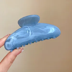 Primo piano di una molletta per capelli in acrilico marmorizzato blu e bianco in mano