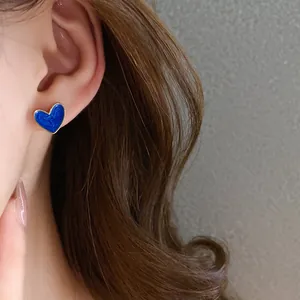Detailed view of an elegant blue heart-shaped enamel stud earring with a refined gold rim