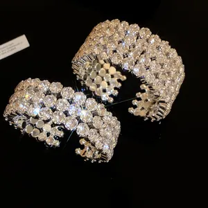 Close-up of wide silver-tone cuff bracelets encrusted with sparkling round-cut crystals.