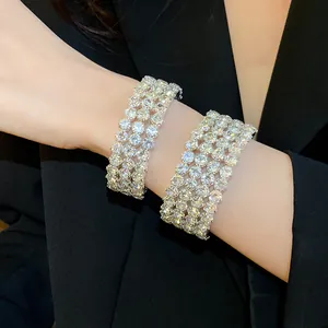 Close-up of model wearing multi-row sparkling rhinestone open bracelets on black blazer