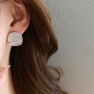 Close-up of elegant Korean style drip oil stud earring with golden frame worn on a female ear