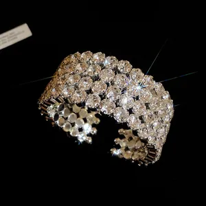 Close-up shot of sparkling round rhinestones on a wide silver-toned metal cuff bracelet