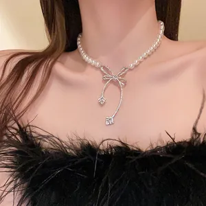 Close-up of elegant baroque pearl necklace featuring a sparkling crystal bow pendant on a model