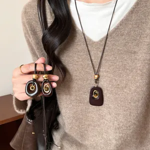 Primo piano di una collana ovale in resina occhio di tigre su maglione marrone