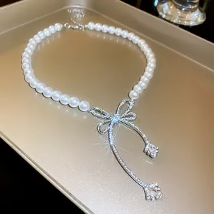 Elegant close-up of a pearl necklace with a shimmering rhinestone-encrusted bow pendant