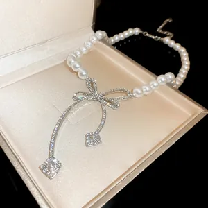 Detailed view of an elegant pearl necklace with a sparkling rhinestone bow pendant